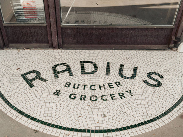 Curved custom logo mosaic at a butcher and grocery entrance