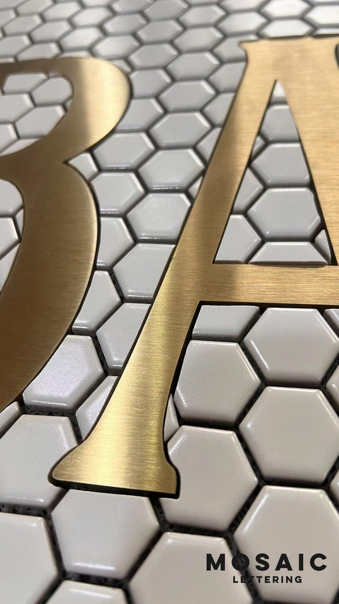 Gold metal letter set into hexagon tile