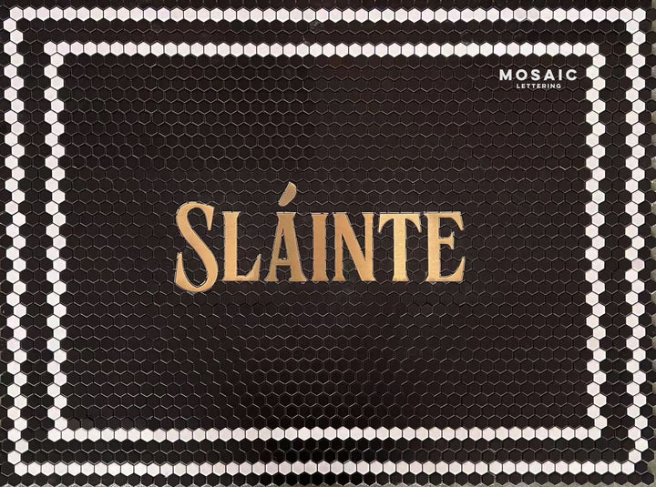 Sláinte gold on black hexagon, bar logo mosaic by Mosaic Lettering, photographed at our studio before installation